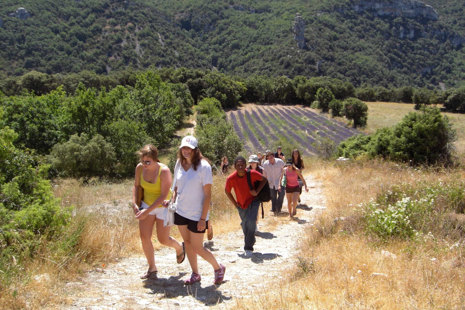 CEI students hiking on a trail in Provence with a lavender field in the background during their stay in France.