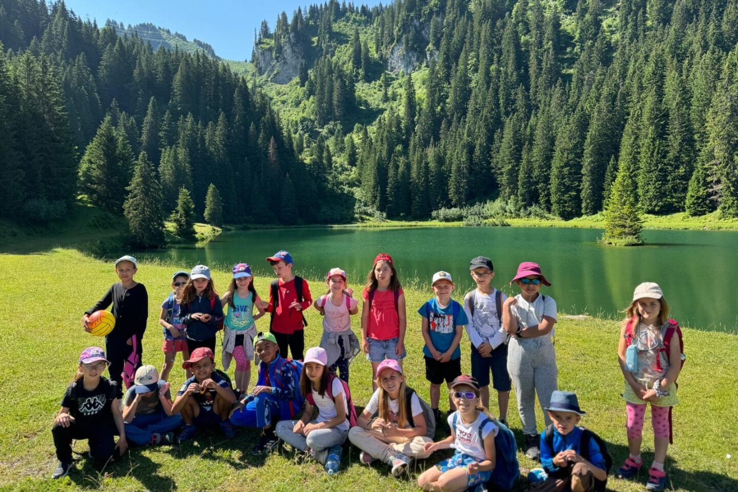 Enfants en colonie de vacances à Châtel posant devant un lac de montagne pendant une randonnée dans les Alpes