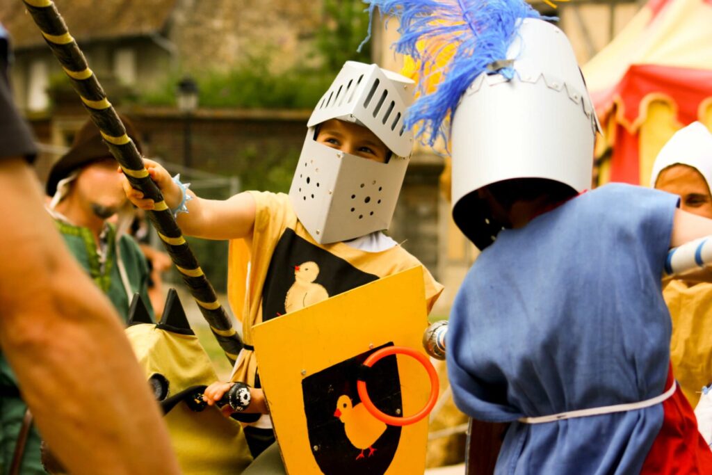 Enfants déguisés en chevaliers participant à un jeu médiéval pendant une colonie de vacances enfants.