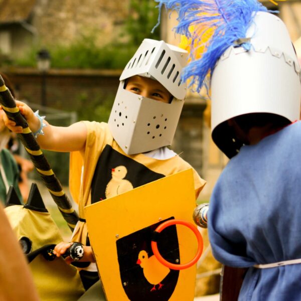 Enfants déguisés en chevaliers participant à un jeu médiéval pendant une colonie de vacances enfants.