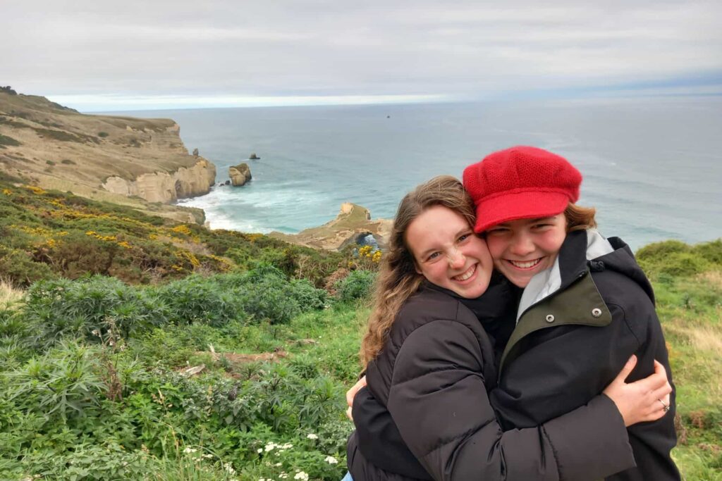 Deux lycéennes souriantes sur une falaise, illustrant l'amitié et l'épanouissement personnel lors d'un programme d'échange scolaire international avec le CEI.