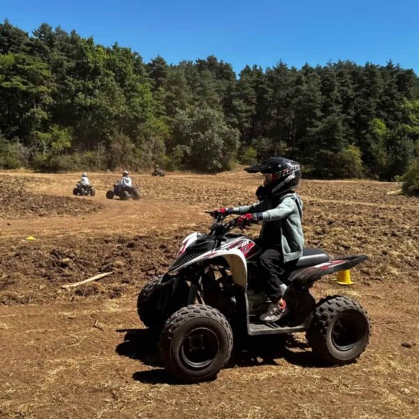 Enfant pilotant un quad sur un circuit en plein air pendant une colonie de vacances quad.