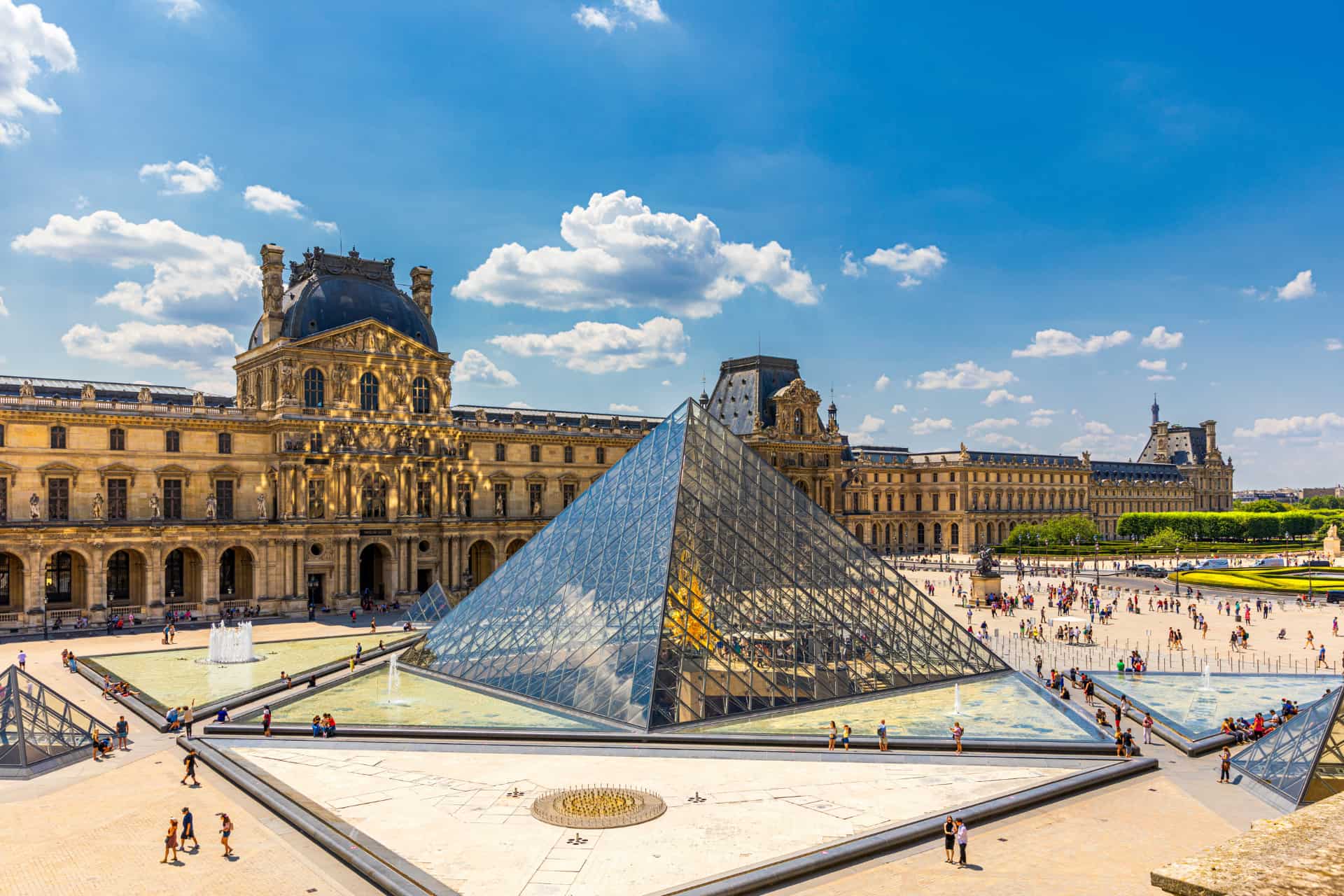 Louvre Pyramid and historic Louvre Palace in Paris under a blue sky