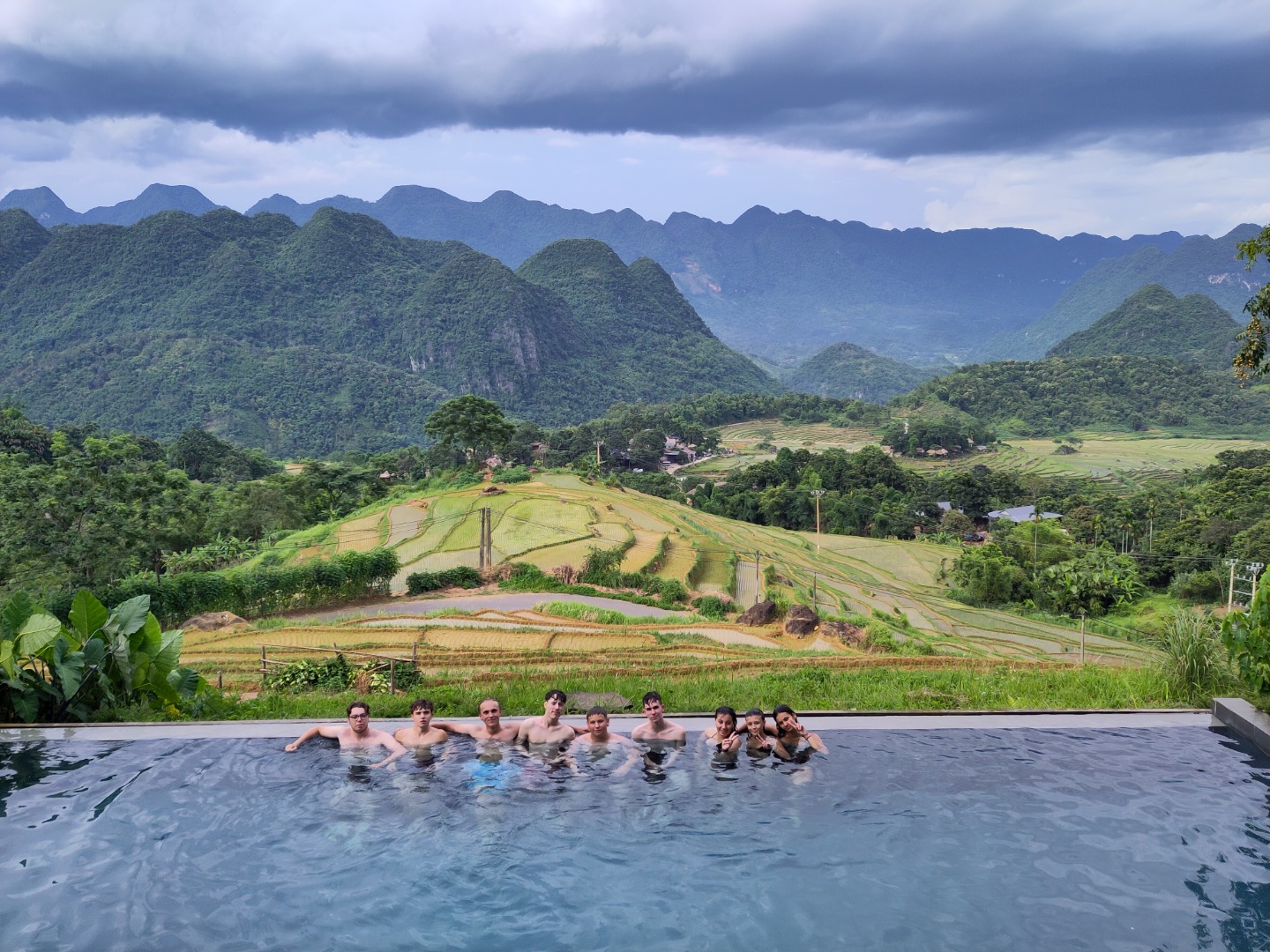 Adolescents en colonie CEI profitant d’une piscine avec vue sur les rizières et montagnes de Mai Chau, Vietnam.