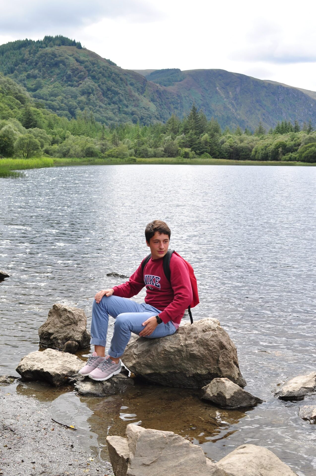 Adolescent profitant d’un paysage naturel en Irlande, au bord d’un lac entouré de montagnes verdoyantes